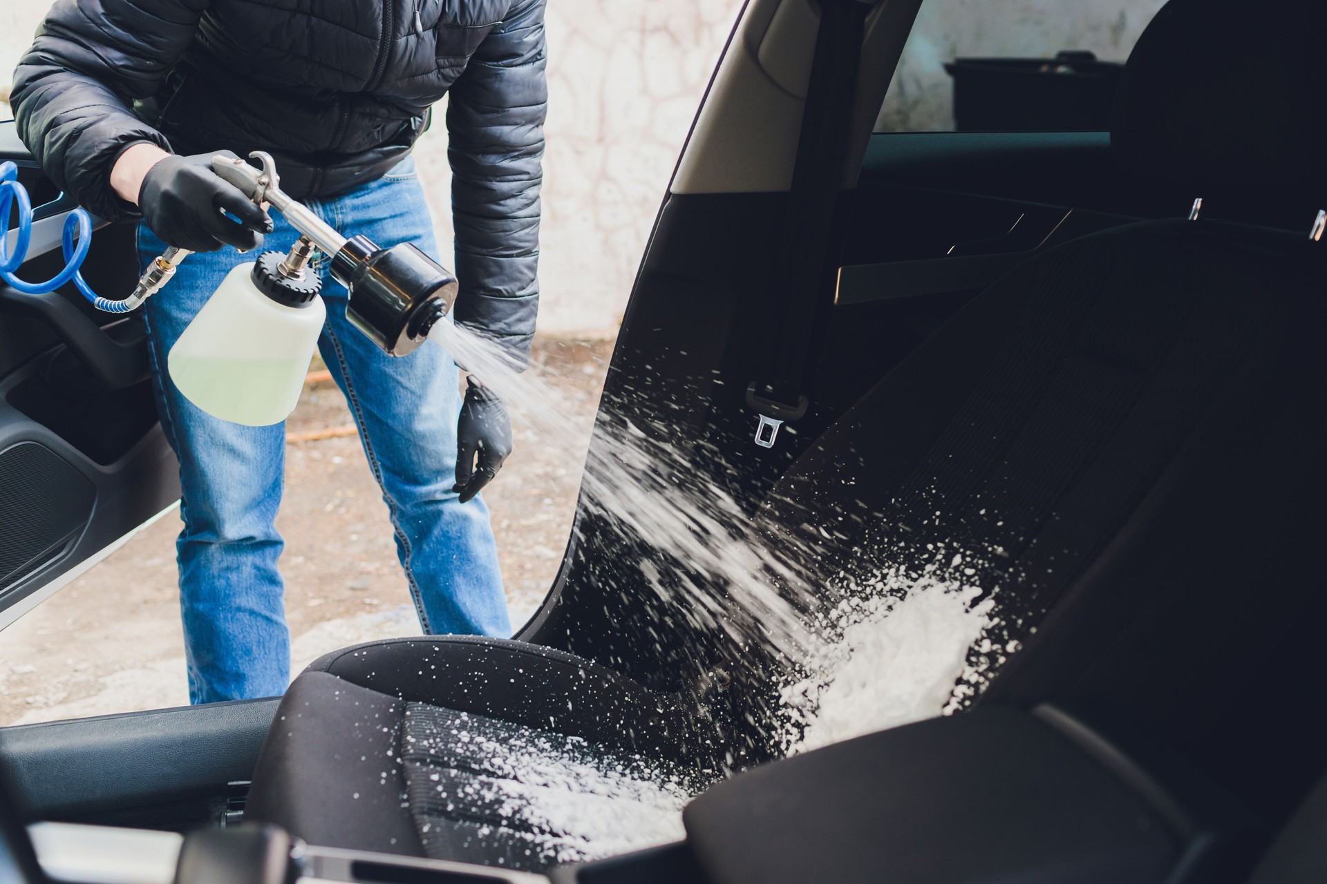 un homme nettoyant l’intérieur de voiture par l’utilisation chimique de mousse et machine de nettoyage.